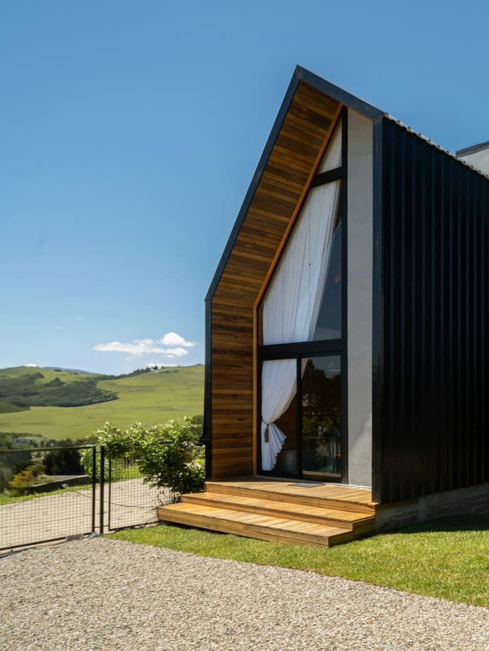 Maison contemporaine à double pignon, couverture métallique sombre et débords en bois